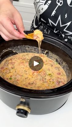 a person is adding tortilla chips to a slow cooker filled with food