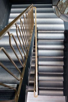 an overhead view of a stair case with metal handrails and carpeted flooring