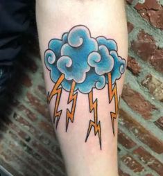 a blue cloud with lightning bolt tattoo on the arm