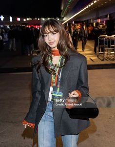 a woman is standing outside at night with her hand in her pocket and holding a purse