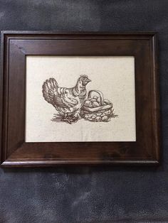 a framed drawing of two chickens sitting on a table next to each other in front of a black wall