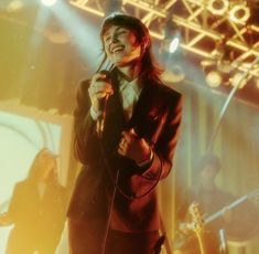 a woman singing into a microphone on stage