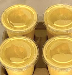 six yellow plastic cups with lids in a cardboard box