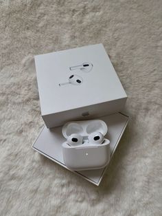 an open box with two white airpods in it on top of a fluffy surface