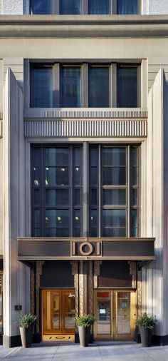 an entrance to a large building with two planters on the sidewalk in front of it