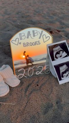 there is a baby's photo and shoes on the sand near an easel