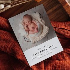 a card with a photo of a baby in a basket on top of a wooden table