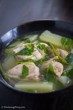 a black bowl filled with chicken and vegetables