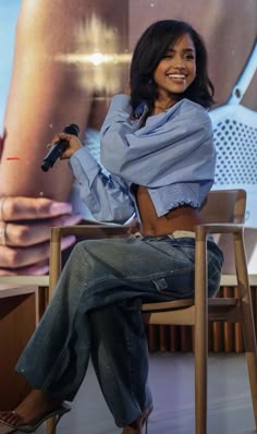 a woman sitting in a chair holding a microphone