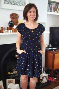 a woman standing in front of a fire place with her hands on her hips and looking at the camera