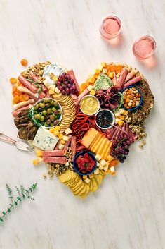 a heart shaped platter filled with meats, cheeses, and other foods