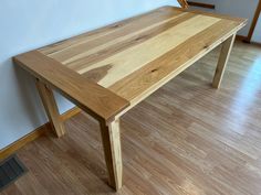 a wooden table sitting on top of a hard wood floor next to a white wall