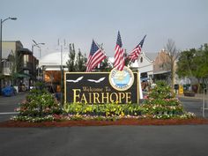 welcome to fair hope sign surrounded by flowers and american flags in front of the town center