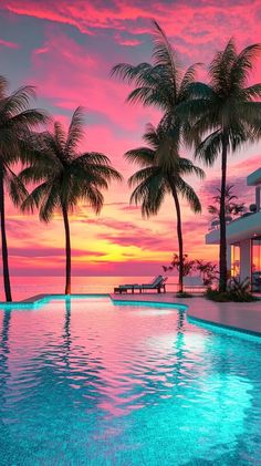 the pool is surrounded by palm trees as the sun sets over the ocean in the background