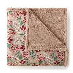 a blanket with red and green flowers on it, sitting next to a white wall