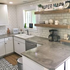 a kitchen with white cabinets and stainless steel counter tops, black and white rug on the floor