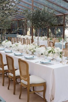 a long table with white flowers and greenery is set up for a formal function