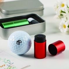 two golf balls, one red and one white with the letter m next to it