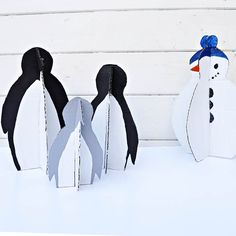 three paper penguins are standing next to each other