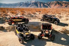 four can - am vehicles parked in the desert with mountains in the background