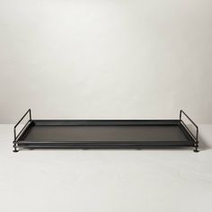 a black tray sitting on top of a white table next to a light fixture and a wall