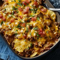 a casserole dish with meat, cheese and vegetables in it on a blue cloth