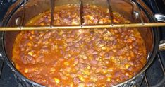 a pot filled with chili and beans cooking on top of an open stove burner