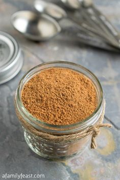 a glass jar filled with spices next to spoons