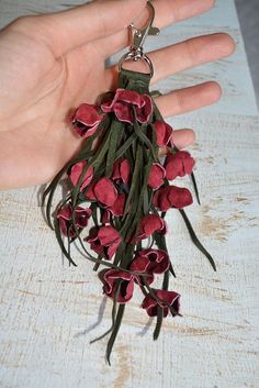 a person's hand holding a bunch of red flowers on a keychain