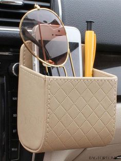 a cell phone and sunglasses in a beige holder on the dashboard of a car,