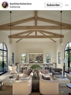 a living room filled with lots of furniture and large windows in the wall above it