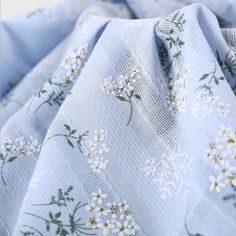 the fabric is blue with white flowers and green leaves on it's side,