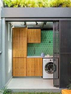 an outdoor kitchen with green tiles and wooden cabinets, as well as a washer and dryer