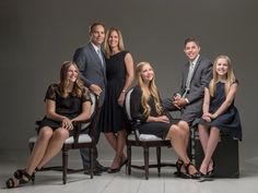 a group of people sitting next to each other posing for a photo in front of a gray background