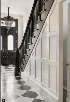 a black and white checkered floor in a house with stairs leading up to the front door