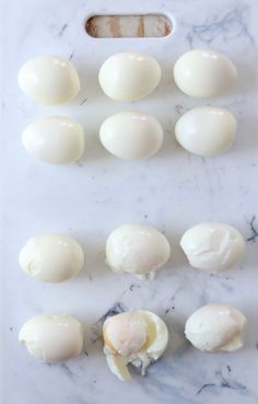 hard boiled eggs laid out on a white marble counter top with one broken egg in the middle