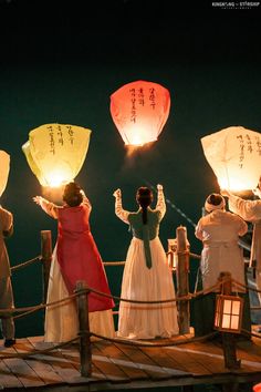 people on a boat holding lanterns in the air