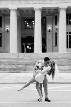 a man and woman kissing in front of a building