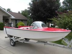 a red and white boat is parked in front of a house