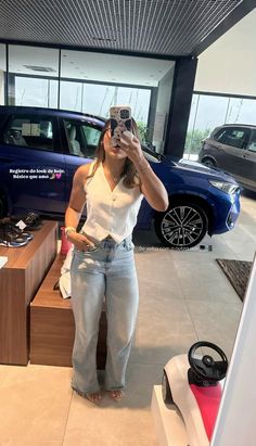 a woman taking a selfie in front of a car dealership with her cell phone