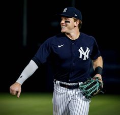 a baseball player wearing a new york yankees uniform and holding a catchers mitt