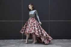 a woman standing in front of a black wall wearing a dress with flowers on it