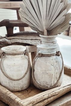 two white vases sitting on top of a wooden tray