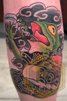 a tattoo design on the leg of a man with a green frog holding a bottle