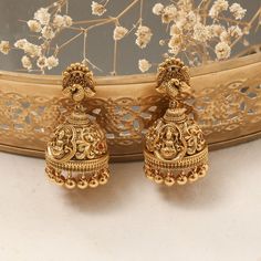 Description: This pair of Nakshi jhumkas exudes divine elegance, featuring the revered Goddess Lakshmi intricately crafted at the center. The detailed Nakshi work enhances the sacred design, making these jhumkas a timeless symbol of grace and tradition. Perfect for adding a touch of spiritual charm to your traditional ensemble, these jhumkas are both a statement of devotion and refined artistry. Product Information: Materials used: 925 Silver with Antique Gold Plating Stones: High Grade CZ Stone Nakshi Jhumkas Gold Earrings, Gold Jumkas Antiques, Jumkas Antiques, Nakshi Jhumkas, Gold Jumkas, Symbol Of Grace, Silver Jhumkas, Sherwani For Men Wedding, Gold Jhumka