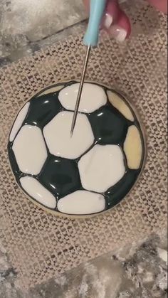 a person is using a needle to paint a black and white soccer ball