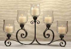 an iron candelabra with candles in it on a white tableclothed surface