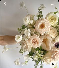 a bouquet of white and pink flowers in someone's hand on a white background