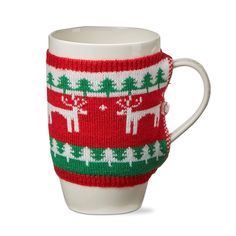 a knitted coffee cup cover with reindeers and trees in red, green and white