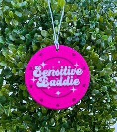 a pink sign hanging from the side of a green bush that says,'seductive baddie '